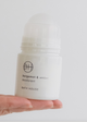 Roll-on deodorant bottle held in a hand against a plain background