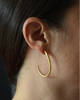 Close-up of a person wearing a gold hoop earring with a dark background