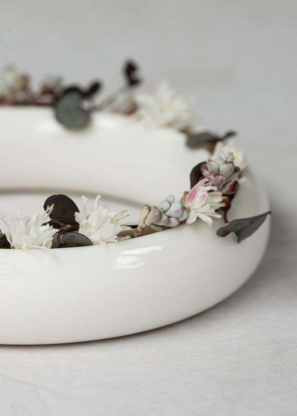 Floral wreath on a white ceramic vase against a light background